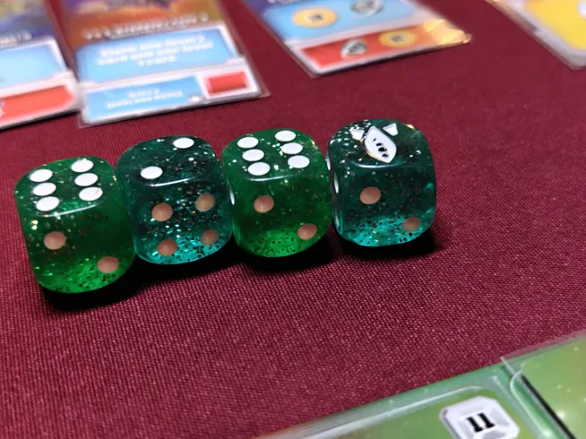 A picture showing green and dark green dice for the game Space Base